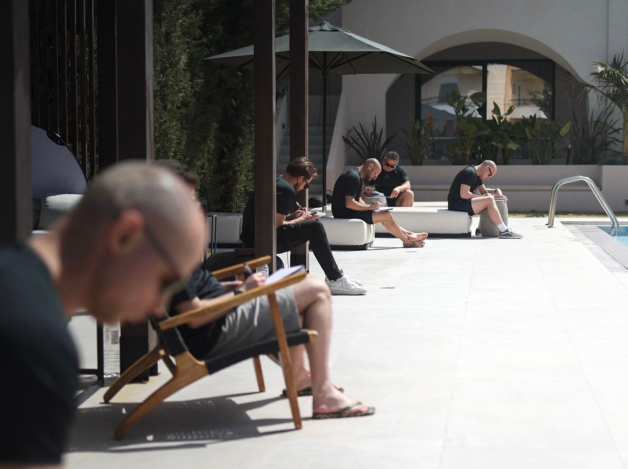 Operators journaling on poolside benches in the morning sun